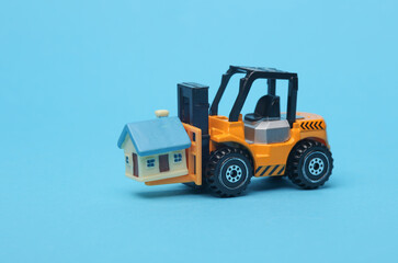 Forklift miniature with house model on blue background