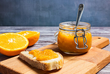 Delicious breakfast with homemade orange marmalade. Homemade orange marmalade in glass jar, slice of bread with orange marmalade.