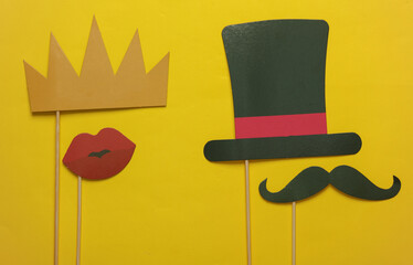 Carnival photo booth hat and mustache, crown and lips on a yellow background.