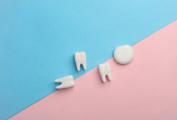Plastic models of teeth and dental floss on a blue pink background. Dental care. Top view