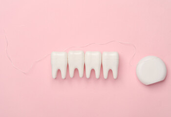 Plastic models of teeth and dental floss on pink background. Dental care. Top view