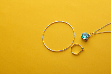 Jewelry silver bracelet, ring and pendant on a yellow background