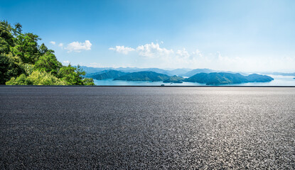 Asphalt road and lake with mountains nature landscape on a sunny day. Beautiful coastline in summer...