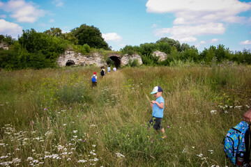 excursion of parents with children to the ruins of an old castle in the grass, arches in an ancient...