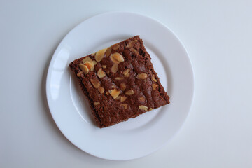Brownies cake with almond topping, on white plate, isolated on white background, flat lay or top view