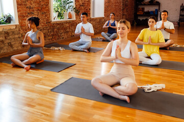 Group of young sporty attractive people practicing yoga lesson with instructor. Multi ethnic women...