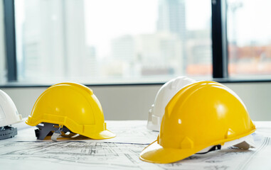 A group of construction workers are wearing yellow hard hats. The hats are placed on a table next...