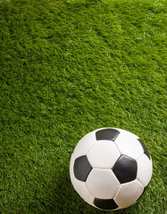 A soccer ball on a green grass field, top view, copyspace on a side