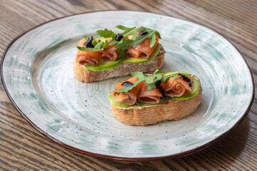Bruschetta with salmon, avocado and arugula on a plate.