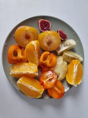 Healthy food including different fruits such as orange, plum, kiwi, higo y kaki