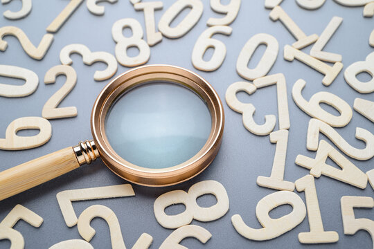 A magnifying glass and random wooden numbers, find the answer about numbers, mathematics learning