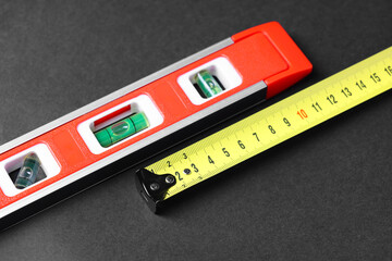 Building level and tape measure on dark background