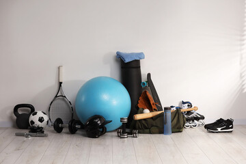 Many different sports equipment near wall indoors