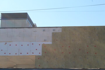 Installing foam insulation board with plastic nails for house energy saving. House foam insulation outdoors.
