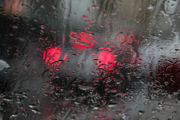 rücklichter von autos durch eine regennasse autoscheibe fotografiert