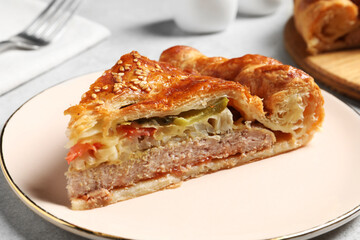 Piece of tasty homemade pie with filling on light grey table