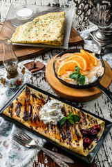 Assorted crepes or pancakes with greens, cheese, cherries, chocolate and meringue on rustic background. Healthy breakfast and lunch, top view