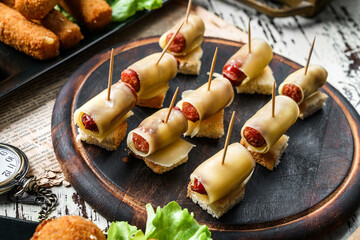Delicious sausages in cheese, canapes on rustic background. Appetizer snack, close up