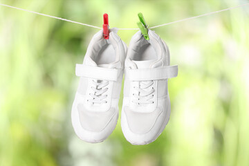 Stylish sneakers drying on washing line against blurred background