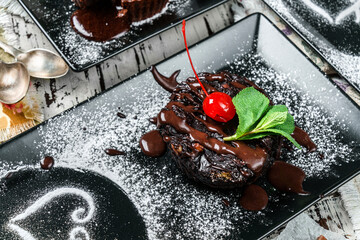 Piece of chocolate brownie cake with chocolate cream and cherries in plate on rustic background....