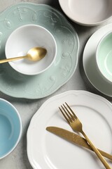 Beautiful ceramic dishware and cutlery on light grey table, flat lay