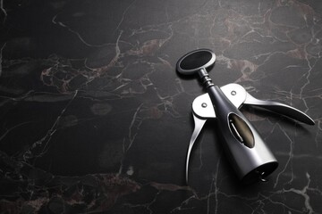 One wing corkscrew on black marble table. Space for text