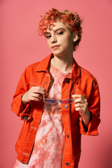 Stylish woman in orange shirt gracefully holding glasses.