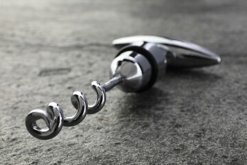 One metal corkscrew on grey textured table, closeup