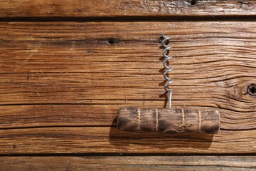One corkscrew on wooden table, top view. Space for text