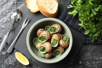 Delicious cooked snails served on grey textured table, flat lay