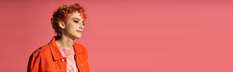 A woman in an orange jacket confidently stands out against a vibrant pink background.