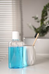 Bottle of mouthwash and toothbrush on white countertop in bathroom