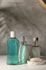 Bottle of mouthwash, toothbrushes and soap on light table in bathroom