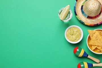 Mexican sombrero hat, guacamole, nachos chips, maracas and tequila on green background, flat lay....