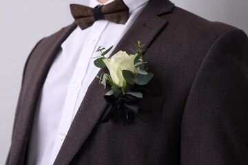 Groom with boutonniere on light grey background, closeup. Wedding accessory - obrazy, fototapety, plakaty