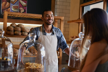 Bakery, happy and man in cafe with customer for serving pastry, cakes and baked foods for small business. Restaurant, coffee shop and waiter or barista by counter for service, help and talk to woman