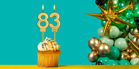 Birthday candle number 83 - Cupcake with decoration on a green background