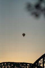 hot balloon in the evening sunset time flying above the city and the bridge