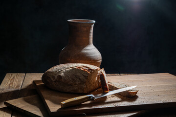 bread and clay vase on a wooden table.