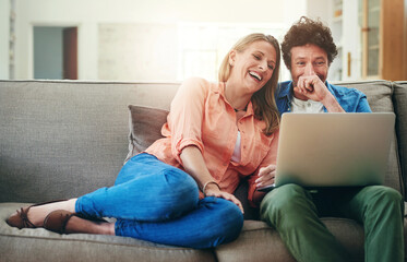 Mature, couple and laughing with laptop on sofa for comedy movie, funny series or streaming service in home. People, technology and comic video on couch with relax, bonding or entertainment in lounge