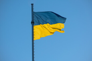 Ukrainian flag stands against the backdrop of a serene blue sky. Symbol of the freedom of Ukrainian nation