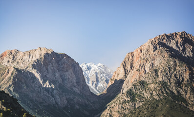 Rocky peaks of mountains and ridges with snow on an early sunny morning