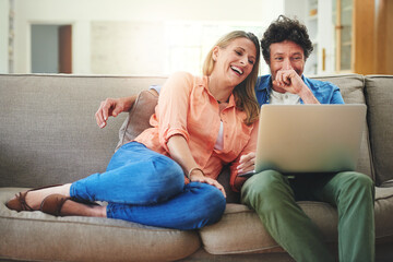 Obraz premium Mature, couple and laughing with laptop on couch for comedy movie, funny series or streaming service in home. People, technology and comic video on sofa with relax, bonding or entertainment in lounge