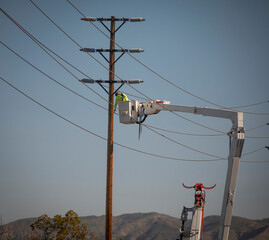 A Man on a manlift working on high electricity lines on a transmission pole