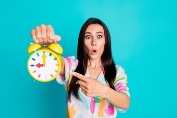 Photo of pretty young woman direct finger alarm clock wear shirt isolated on teal color background