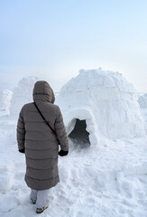 A woman in front of an igloo, a traditional shelter of the northern peoples from the cold, made of...