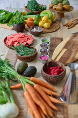 This image features a rich display of fresh vegetables and fruits neatly arranged on a rustic wooden kitchen table. Colorful array of fresh vegetables and fruits on a rustic kitchen table
