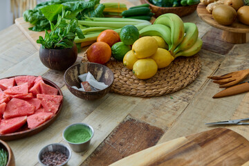 This vibrant image showcases an array of fresh fruits and vegetables spread across a wooden table, ideal for healthy cooking. Featured are lemons, carrots, watermelon.