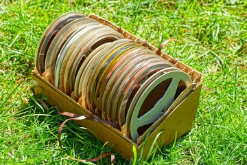 plastic round discarded old ones with brown magnetic tape, retro tape recorder reels in a paper box...
