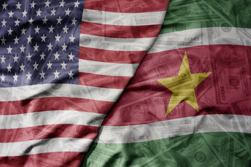 big waving colorful flag of united states of america and national flag of suriname on the dollar money background. finance concept.